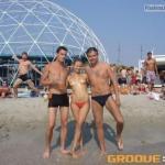 Topless spinner happy to take a photo with two strangers on beach