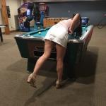 Brunette in short skirt bends over the pool table