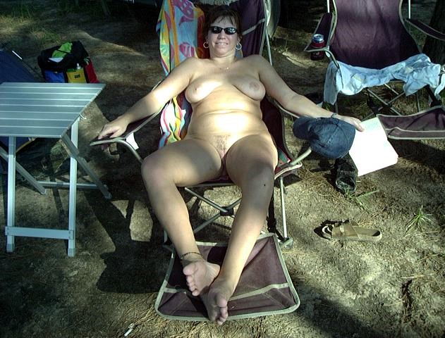 Nude Beach Pics: Late Afternoon Nudist Encounter at Emerald Lake Woman reclines at Emerald Lake Resort, partially clothed in bikini, exuding casual comfort and subtle tension. Late afternoon setting highlights power dynamics.