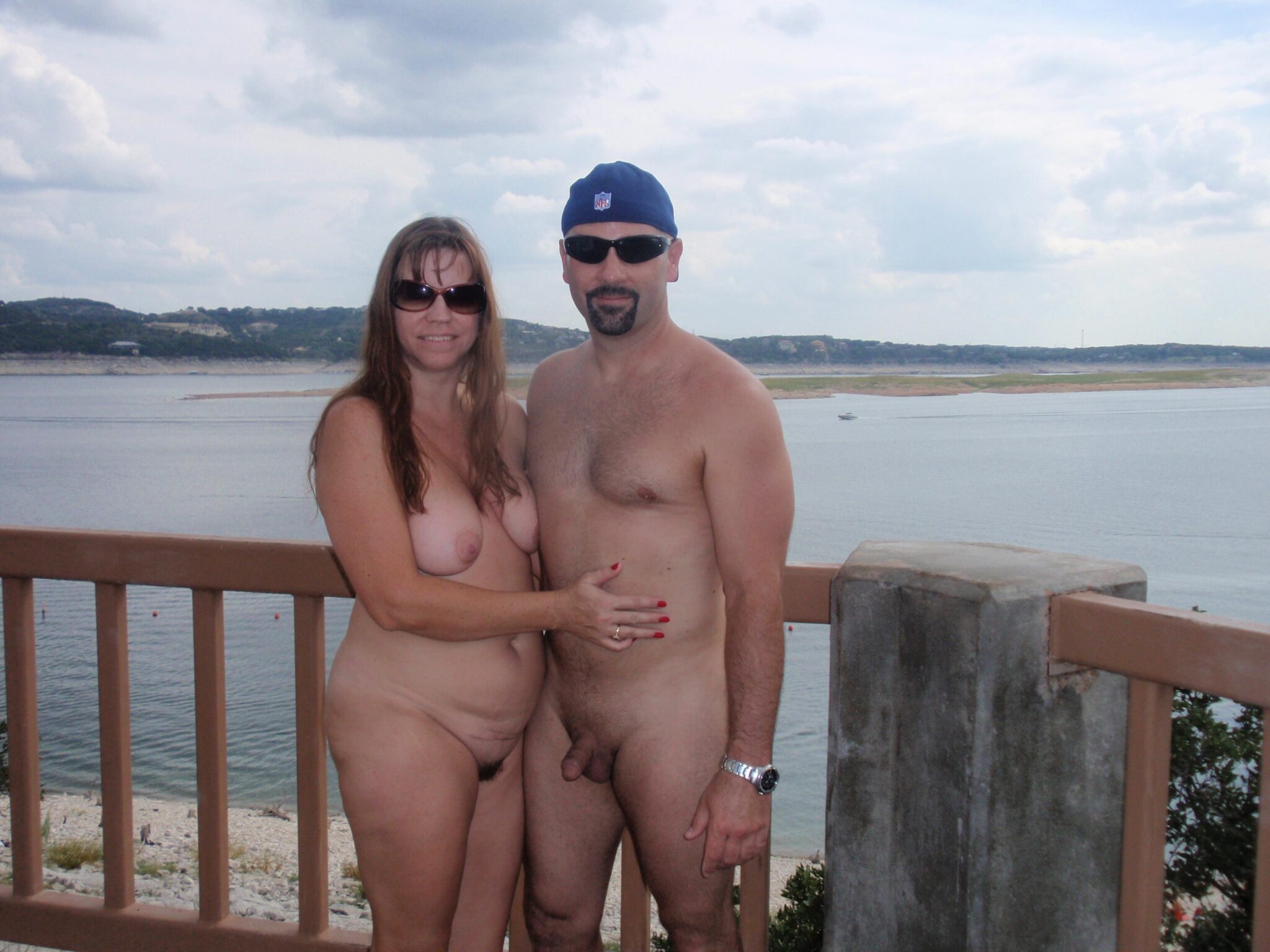 Nude Beach Pics: Hippie Hollow: Naked Couple by the Water A nude couple stands confidently at Hippie Hollow, embracing public nudity with natural ease. The setting offers a serene backdrop, enhancing the casual, uni...